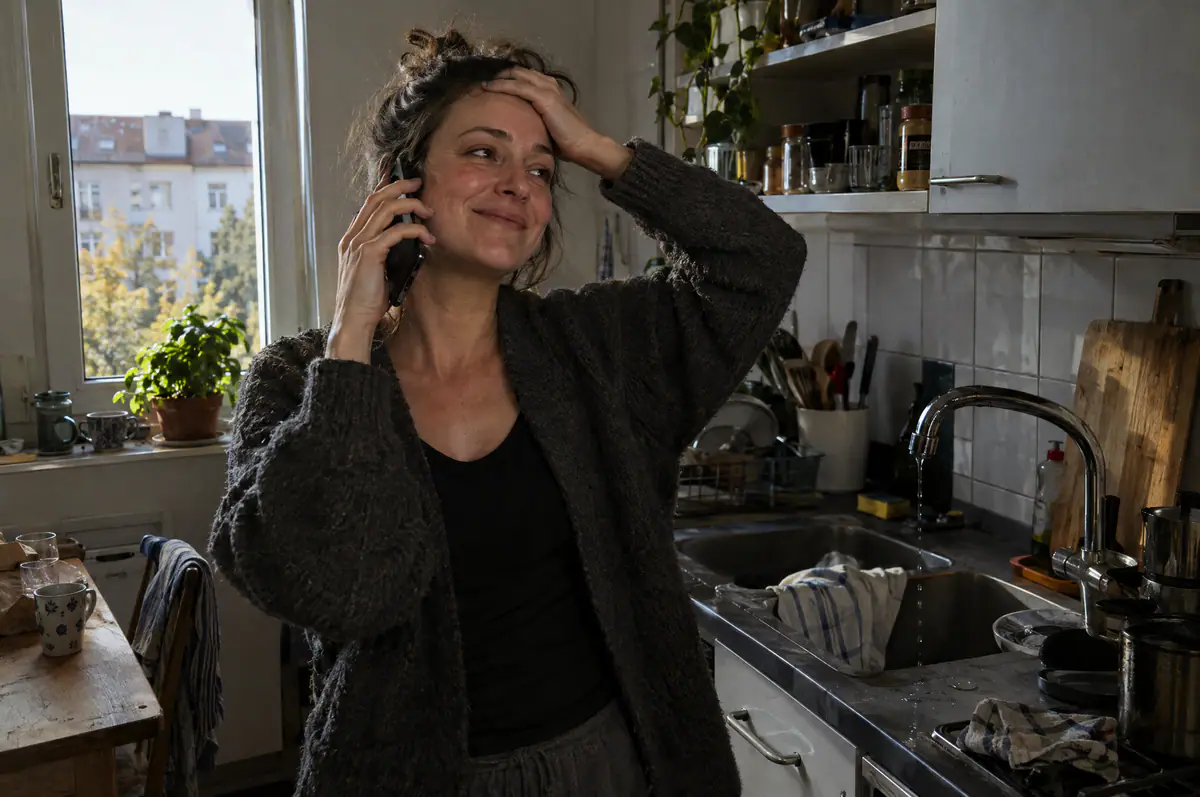 Frau telefoniert erleichtert in ihrer Küche